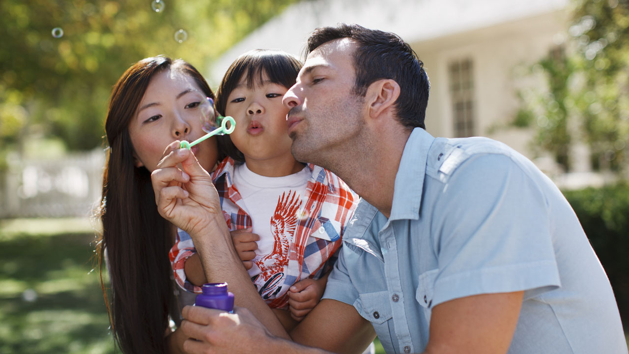 Father and mother blowing bubbles with their daughter