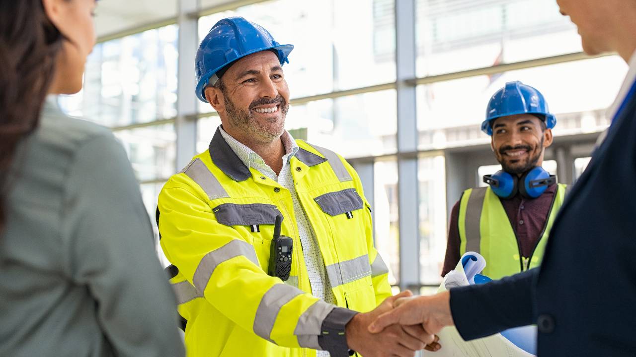 Mature architect and contractor shaking hands at construction site